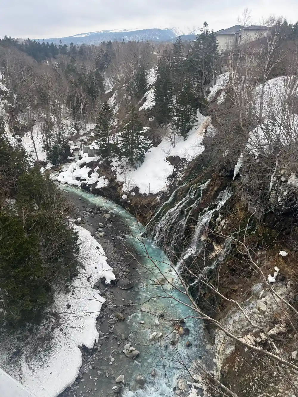 Aerial view of turquoise river winding through snowy forest