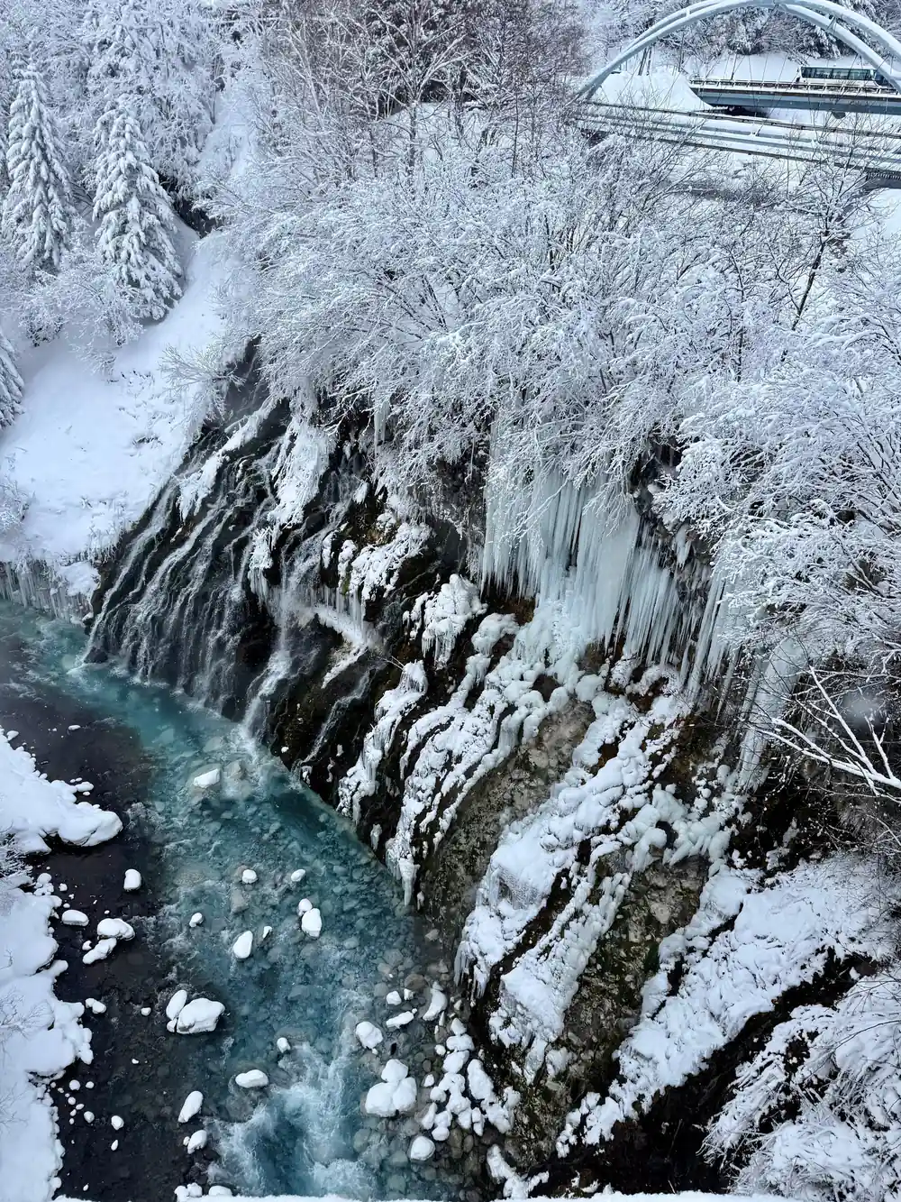Frozen waterfall with turquoise water flowing beneath ice