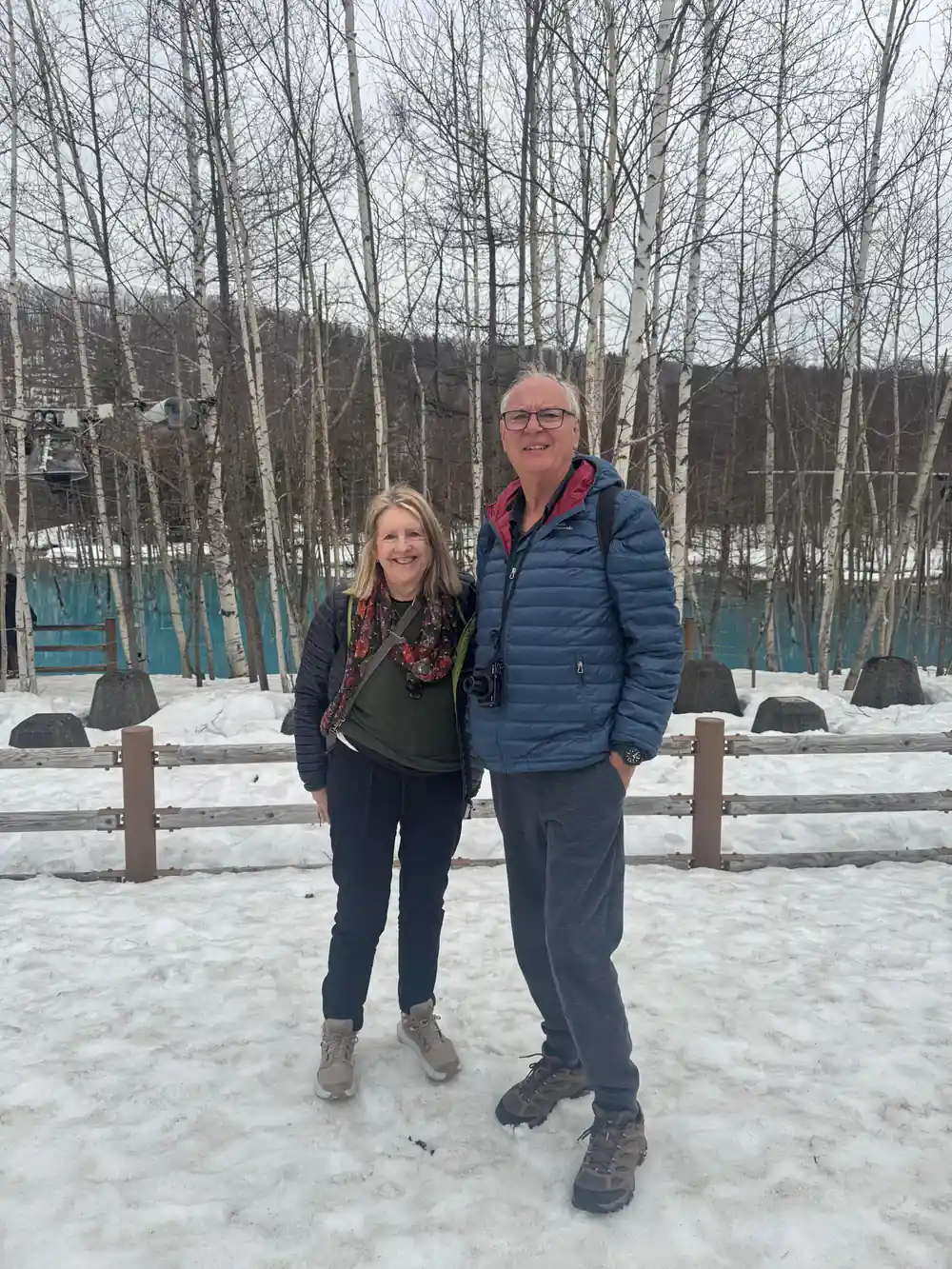 Two people standing on snowy ground near trees