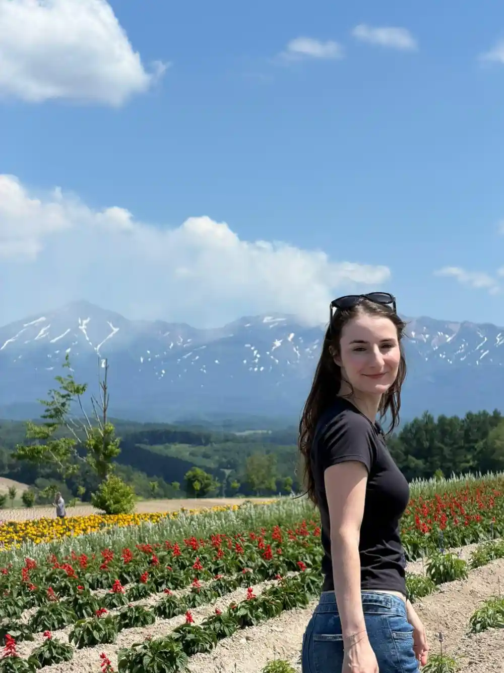 Woman in flower field with snow mountain in background