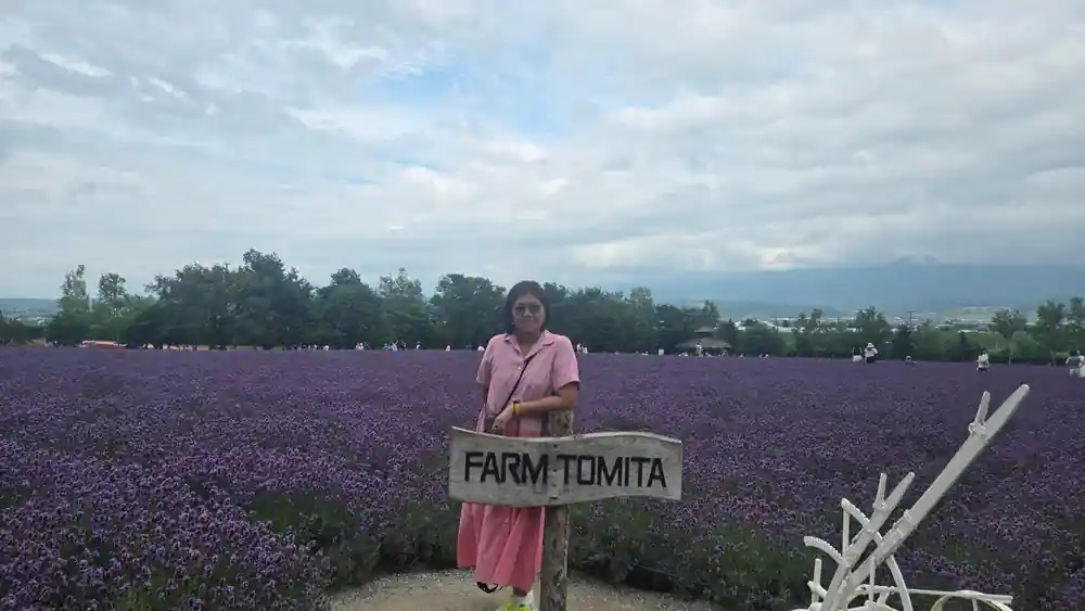Woman in lavender field holding Farm Tomita sign